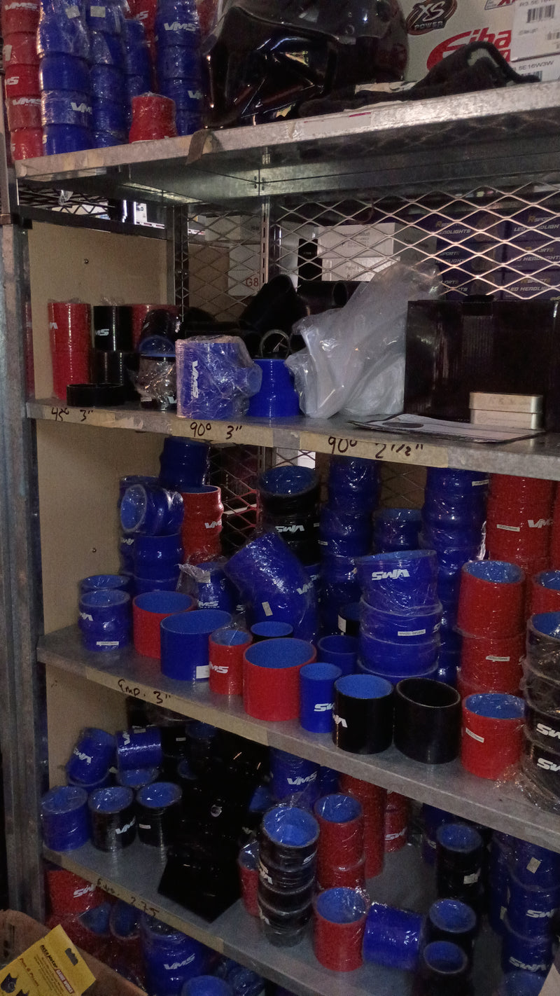 Stacks of blue and red cylindrical silicone hoses and tubes on a metal shelf.